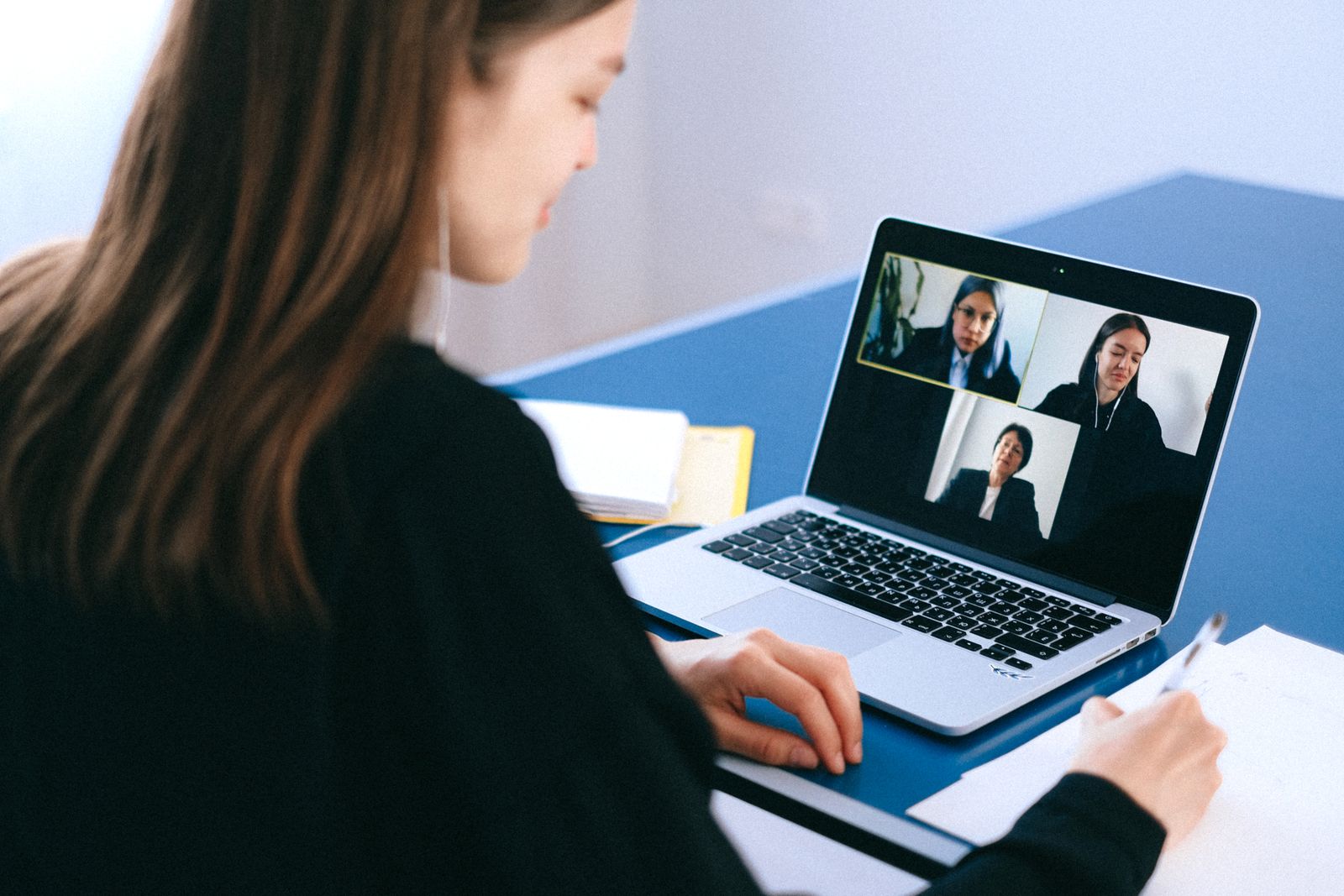 A person on a video call taking notes at a desk, representing a remote planning session